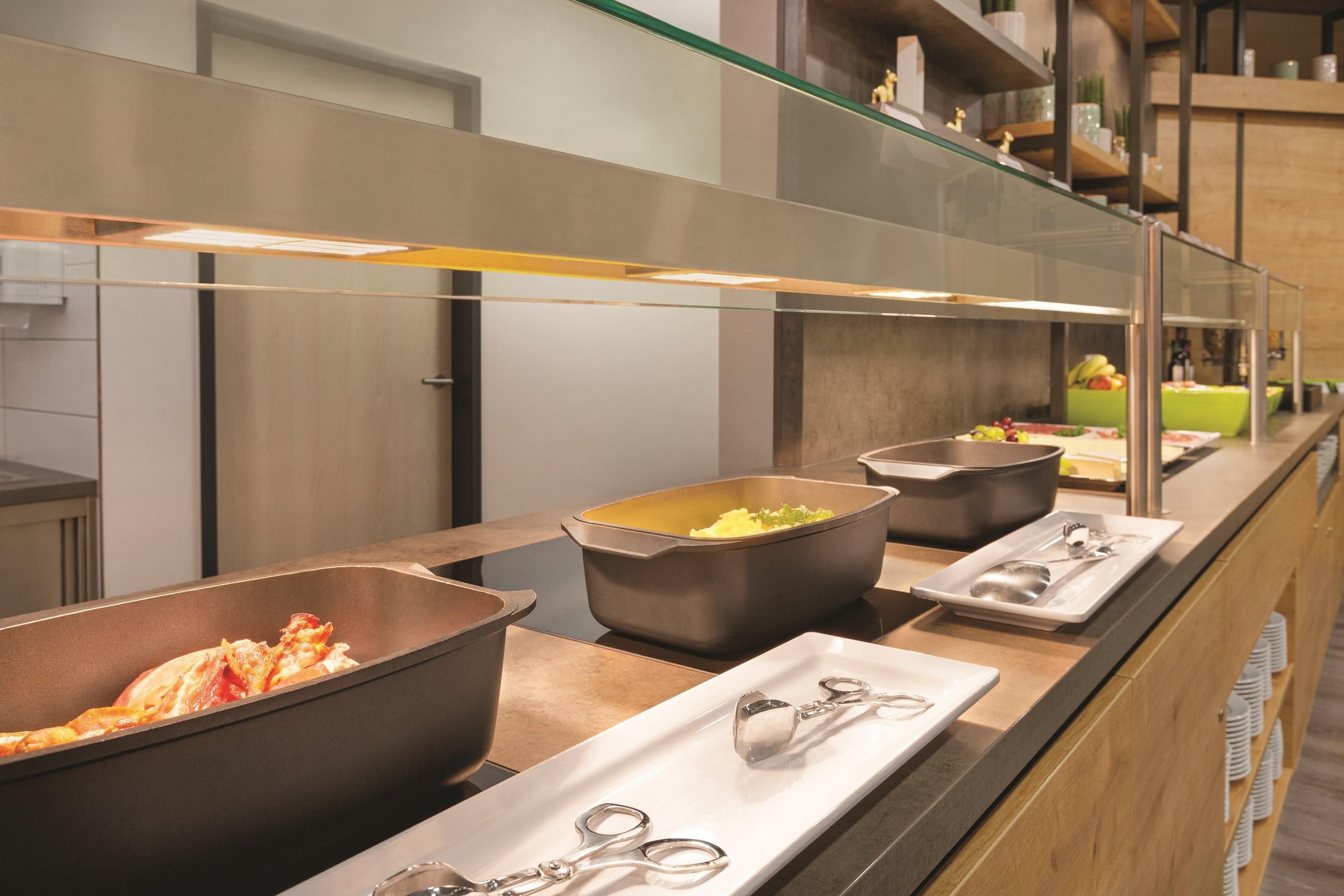 Una mesa de buffet con varios recipientes de comida y utensilios para servir.