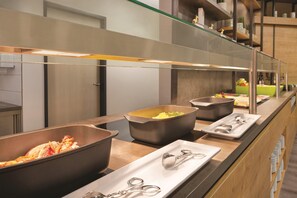 Una mesa de buffet con varios recipientes de comida y utensilios para servir.