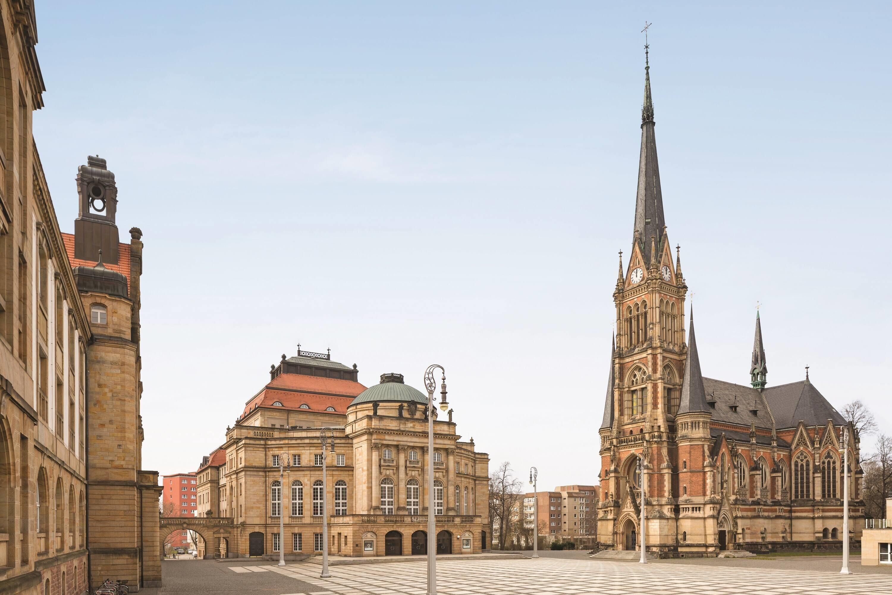 A historic building with a prominent clock tower and a large open square.