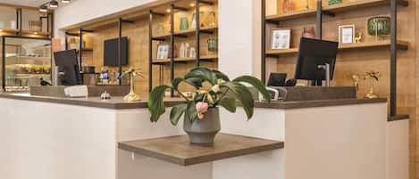 A reception desk with a potted plant, a flat-screen TV, and a counter with various items.