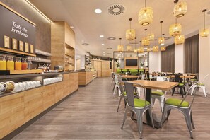 A modern cafe interior with wooden furniture, a bar area with juice dispensers, and pendant lighting. - Super 8 by Wyndham Chemnitz (Chemnitz)
