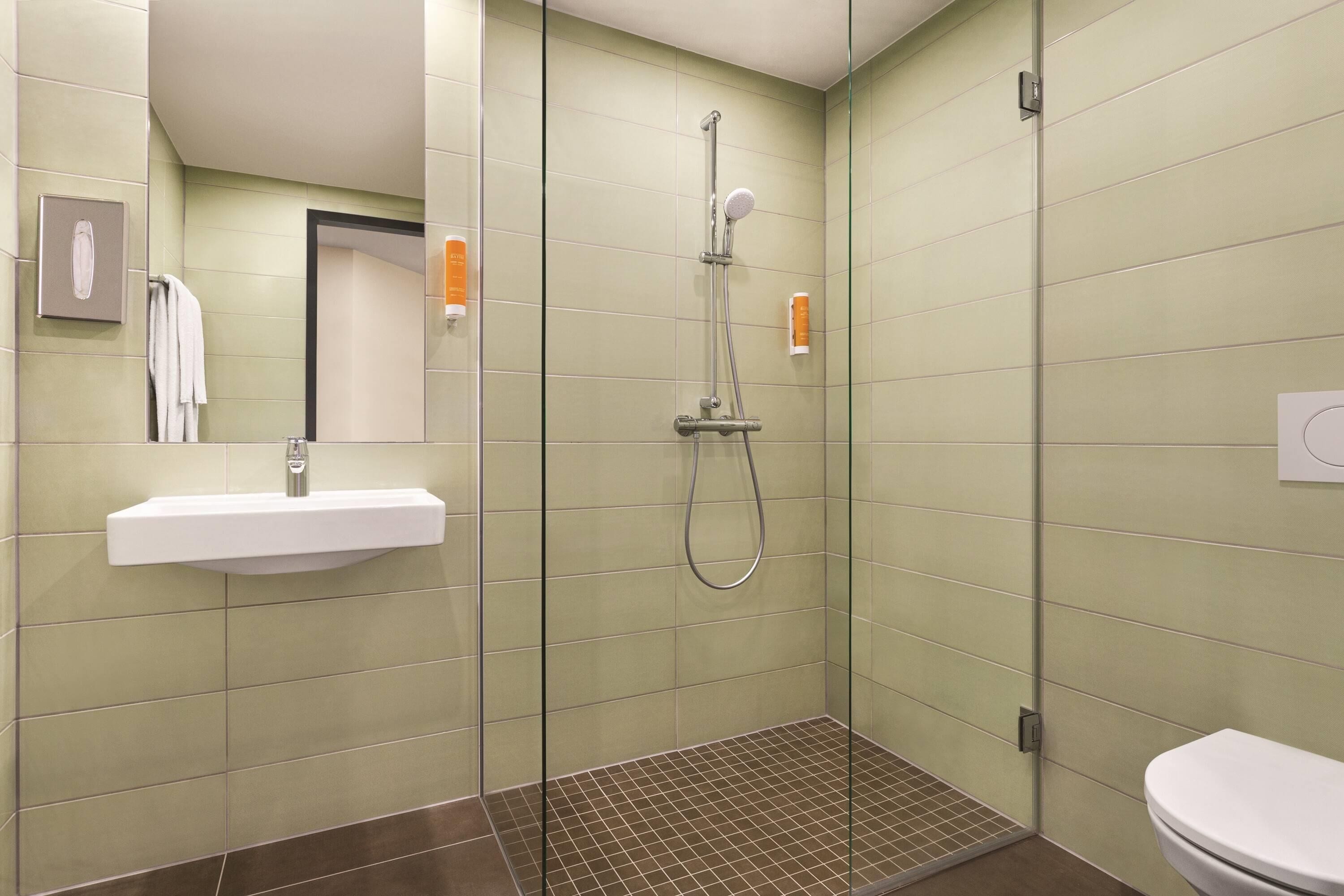 Un baño moderno con ducha envuelta en vidrio, lavamanos y retrete.