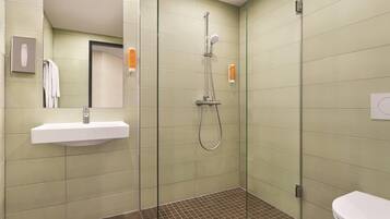 Un baño moderno con ducha envuelta en vidrio, lavamanos y retrete.