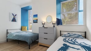 Un dormitorio con dos camas, un aparador, una ventana con persianas y obras de arte en las paredes.