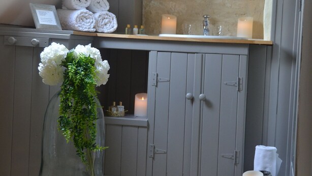A bathroom with a skylight, a vanity with a mirror, and a vase with white flowers. - charming cottage at the gates of Issigeac (Montaut D'issigeac)