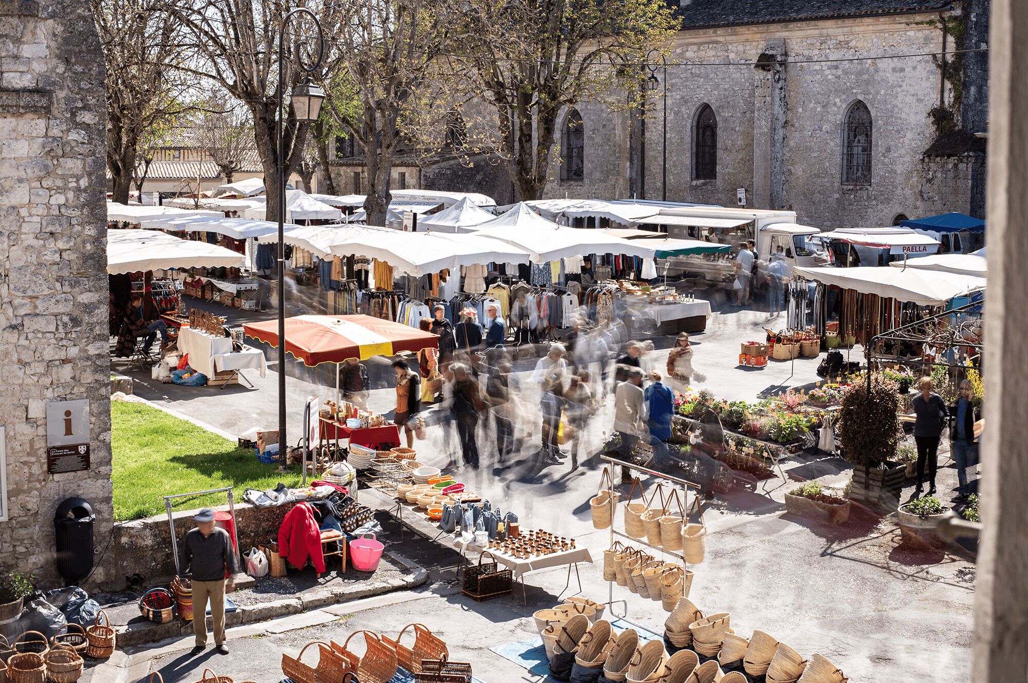 Een openluchtmarkt met verschillende kraampjes die artikelen zoals manden en kleding verkopen.