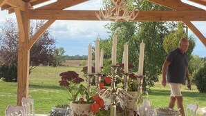 An outdoor dining area with a wooden pergola, a candelabra centerpiece, and a table set for a meal. - charming cottage at the gates of Issigeac (Montaut D'issigeac)