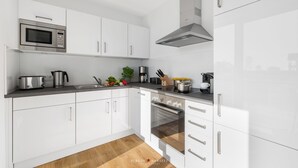 Een moderne keuken met witte kastjes, roestvrijstalen apparatuur en een houten vloer.
