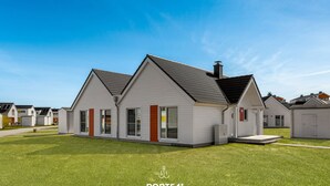 Een modern huis met twee verdiepingen, een schuin dak, grote ramen en een verzorgd gazon.