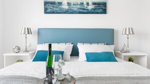 Een keurig opgemaakt slaapkamer met een groot bed, twee nachtkastjes, een schilderij aan de muur en een bedlampje.