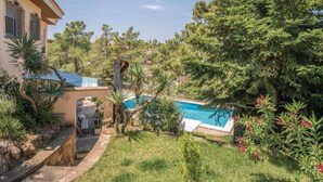 Une piscine entourée d’une végétation luxuriante et un bâtiment doté d’un toit en tuiles.