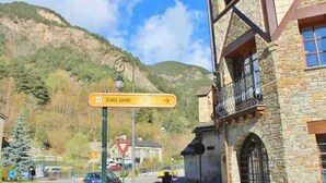 A street view with a sign for 'Kalet Janel' and a stone building with a balcony. - Appartement 1.1 (Erts)