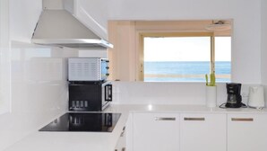 A modern kitchen with white cabinets, a black microwave, and a coffee maker.