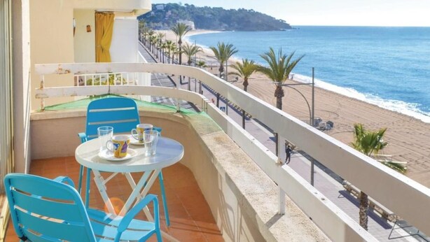 A balcony with a table and chairs overlooking a beach.