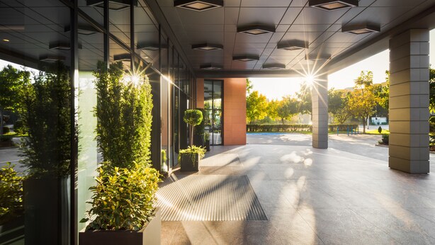 A modern building entrance with glass doors, potted plants, and a tiled floor. - Hotel Jägerhof (Plovdiv)