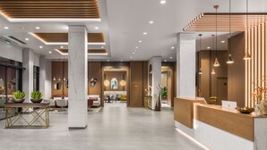 A modern hotel lobby with a reception desk, seating area, and a dining space. - Hotel Jägerhof (Plovdiv)
