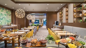 A restaurant with multiple dining tables, a variety of food displayed on platters, and hanging spherical light fixtures. - Hotel Jägerhof (Plovdiv)