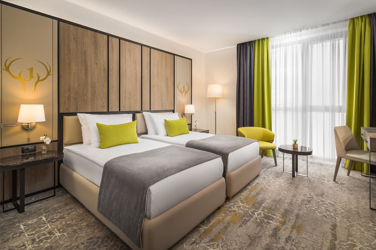 Une chambre d’hôtel avec deux lits, un bureau, une chaise et une petite table.
