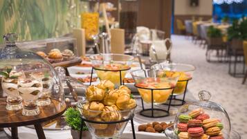 Ein Buffet mit verschiedenen Speisen, darunter Gebäck, Desserts und Früchte.