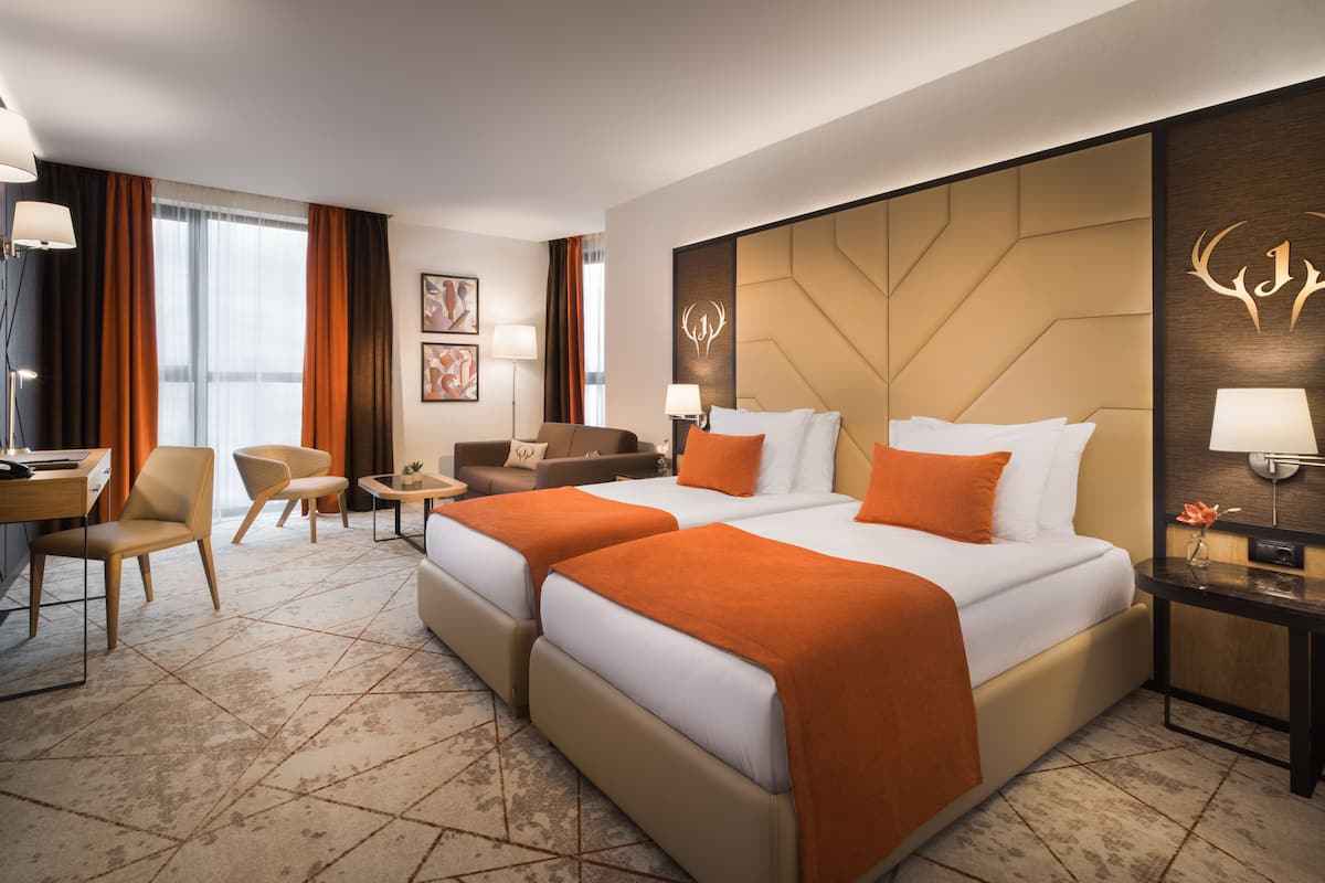 Une chambre d’hôtel avec deux lits, un bureau, une chaise, une petite table et un canapé.