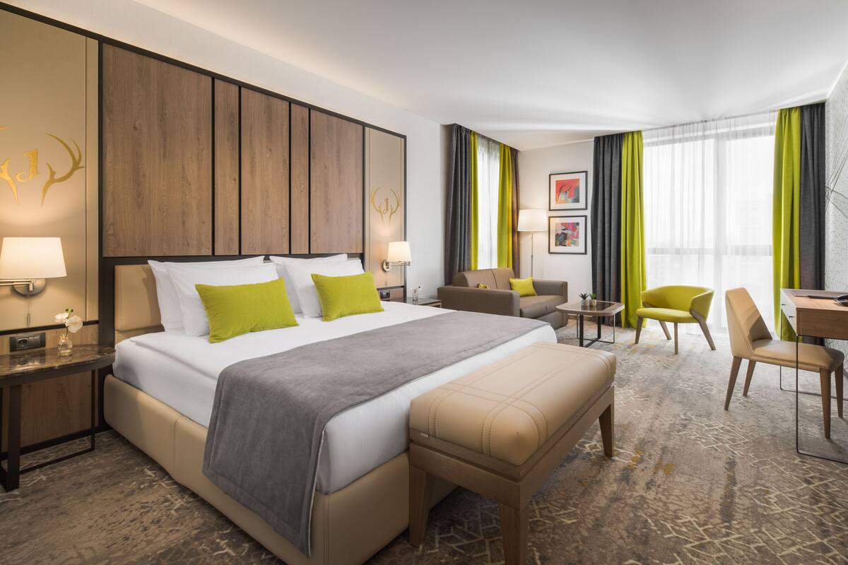 Une chambre d’hôtel avec un grand lit, un bureau, une chaise et un canapé.