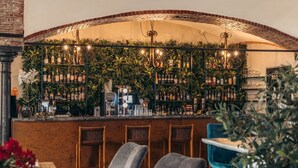 Zona de bar con pared de ladrillo, estantes con botellas y techo curvo.