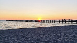Una playa con un muelle que se adentra en el agua durante el atardecer.