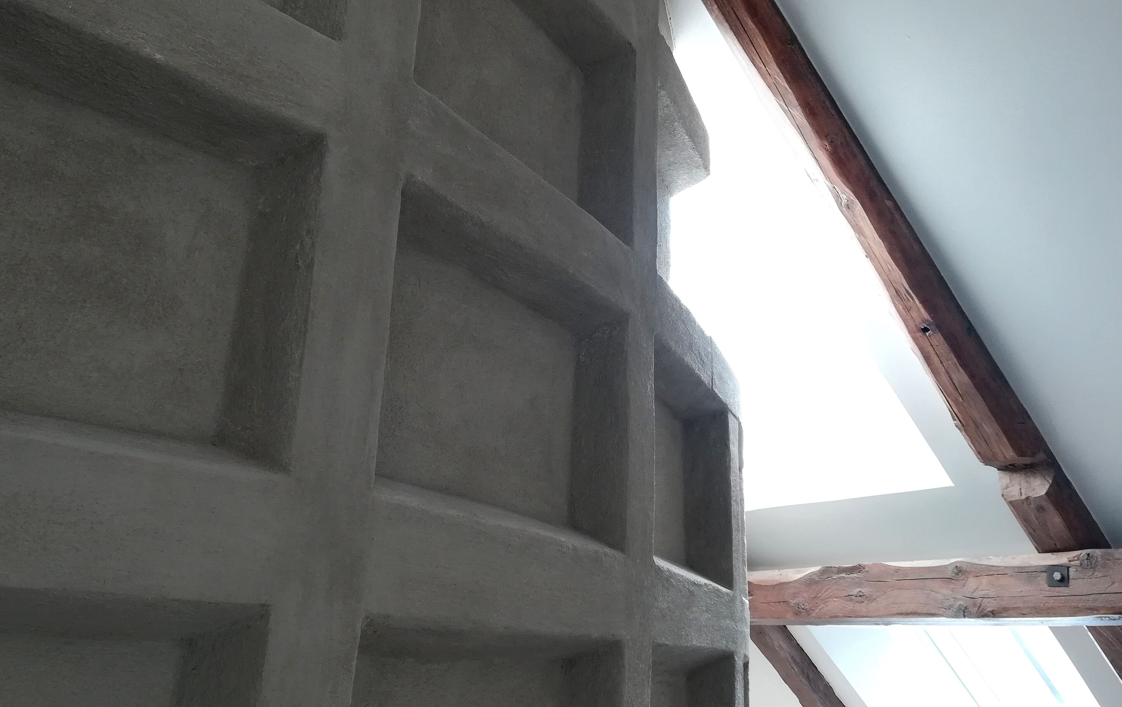 A ceiling with a grid pattern and wooden beams.