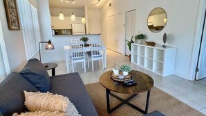 A modern living room with a sofa, coffee table, and dining area.