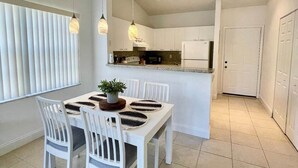 A modern kitchen with white cabinetry, a central island, and pendant lighting.