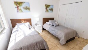 A hotel room with two single beds, a nightstand with a lamp, and a door. - 320B - Boca Retreat w/ Pool, Parking, Near Evert Tennis & Shops (Boca Raton)