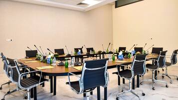 A conference room with a large oval table, black chairs with wheels, and microphones.