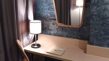 A corner desk with a chair, a lamp, and a mirror.