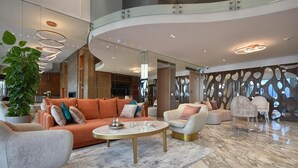 A spacious lobby with a curved seating area, a marble floor, and modern lighting fixtures. - Flower Town Hôtel & Spa (Rabat)