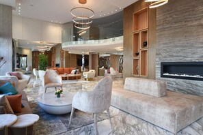 A spacious lobby with modern furnishings, a fireplace, and a glass railing overlooking the interior. - Flower Town Hôtel & Spa (Rabat)