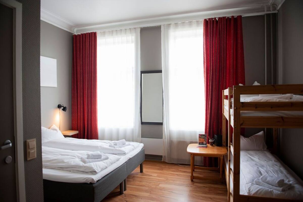 A hotel room with a bed, a desk, and a bunk bed.