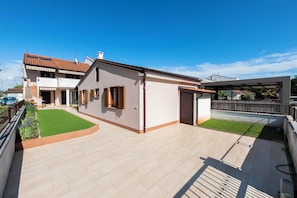 A two-story house with a tiled roof, a covered patio, and a small lawn. - Apartments Pataj (Rovinj)