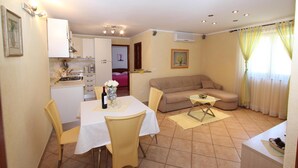 A compact living space with a dining area, kitchenette, and a sofa.