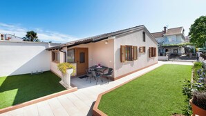 A residential property with a patio, a small garden, and a white exterior wall.
