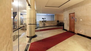 A hotel lobby with a marble floor, a red carpet, a wooden door, and a potted plant. - Rio Spot Homes D050 (Rio de Janeiro)