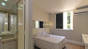 A bedroom with a bed, a nightstand, a mirror, and a window. - Rio Spot Homes D050 (Rio de Janeiro)