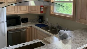 A kitchen with wooden cabinets, a stainless steel sink, a microwave, and a coffee maker. - New! Fabulous Farmhouse (Cape Dauphin)