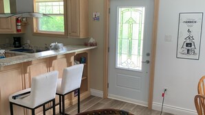 A kitchen with wooden cabinets, a window, and a door with a stained glass design. - New! Fabulous Farmhouse (Cape Dauphin)