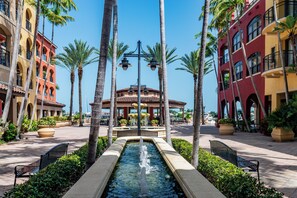 A courtyard with a central fountain, surrounded by palm trees and benches. - Luxury 3 Bed  Condo at Popular Esplanade Overlooking Smokehouse Bay (Marco Island)