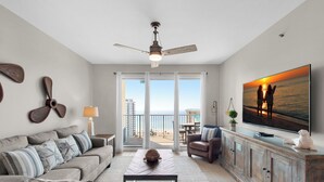 A living room with a sofa, a coffee table, a TV, and a balcony with a view. - 🏖️ Walk2Beach-Gulf Views-2 Pools + Kids Fountain-2BR Ariel Dunes I 1408🏖️ (Miramar Beach)