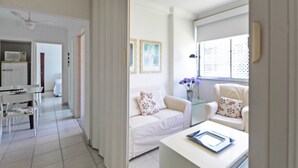 Et moderne, lyst værelse med en hvid sofa, et lille bord og et vindue med udsigt.