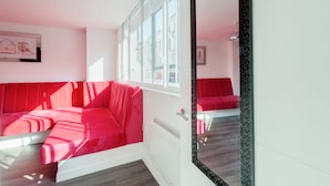 A modern room with a red sofa, a large mirror, and a window with a view of buildings. - iStay Liverpool Bold Street (Liverpool)