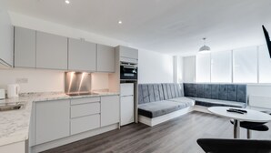 A modern kitchen with white cabinets, a built-in oven, and a marble countertop. - iStay Liverpool Bold Street (Liverpool)