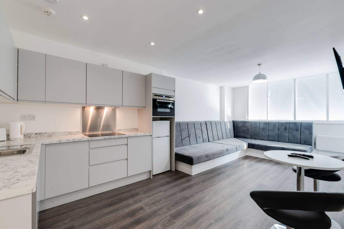 A modern kitchen with white cabinets, a built-in oven, and a marble countertop.