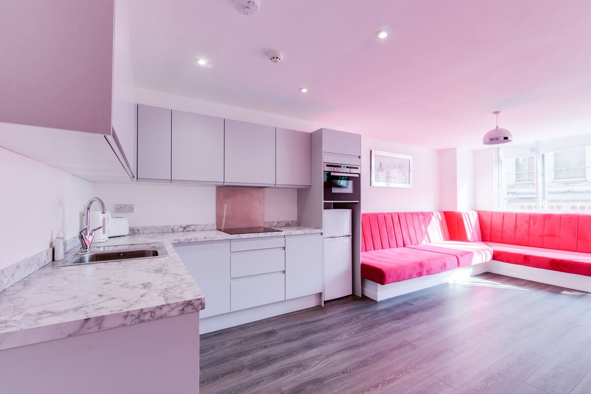 A modern kitchen with white cabinets, a marble countertop, and a built-in oven.